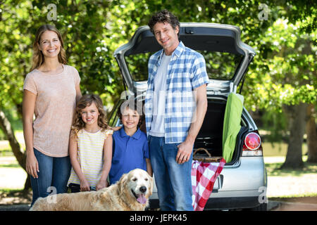 Smiling family standing in front of a car Banque D'Images