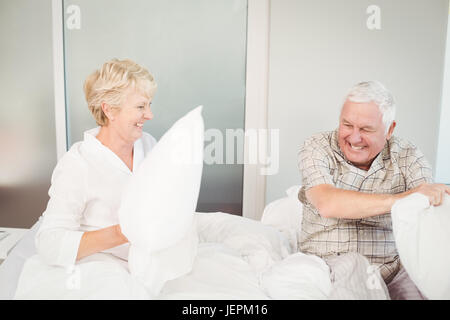 Senior couple having pillow fight in bed Banque D'Images