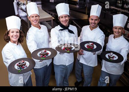 Heureux chefs presenting dessert plates leur Banque D'Images