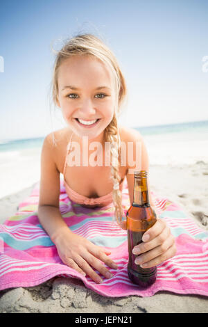 Femme allongée sur la plage avec bouteille de bière Banque D'Images