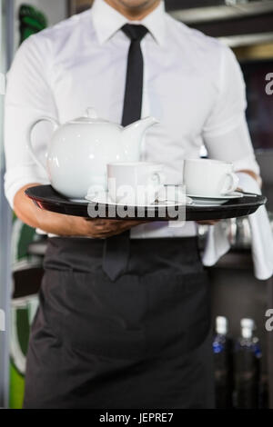 Mid section of waiter serving plateau Banque D'Images