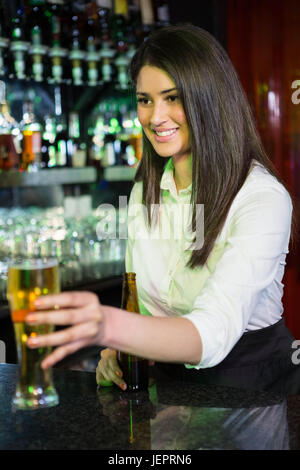 Jolie barman servant de la bière au comptoir du bar Banque D'Images