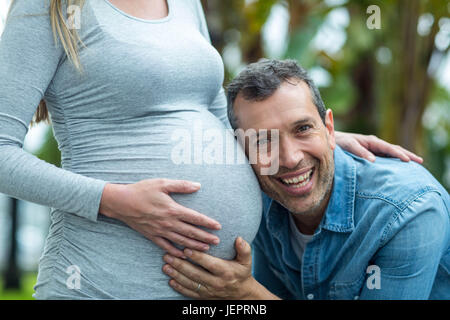 L'homme à l'écoute de l'estomac de femme enceinte Banque D'Images