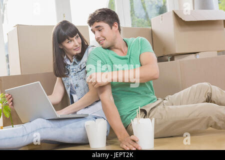 Jeune couple eating noodle and using laptop Banque D'Images