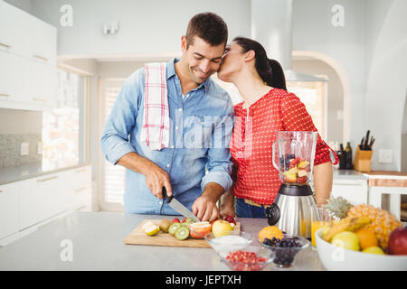 Woman kissing man la préparation de jus de fruits Banque D'Images