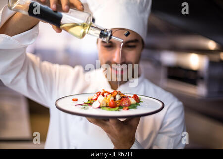 Beau chef pouring olive oil sur les repas Banque D'Images