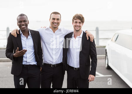 Beaux hommes posant à côté d'une limousine Banque D'Images