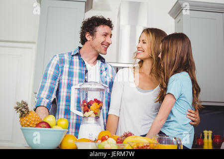 Famille heureuse la préparation de jus de fruits à table Banque D'Images