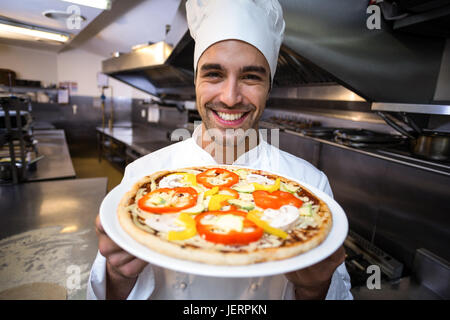 Beau chef presenting pizza Banque D'Images