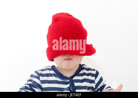 Bébé dans un chapeau rouge tiré sur son visage studio Banque D'Images
