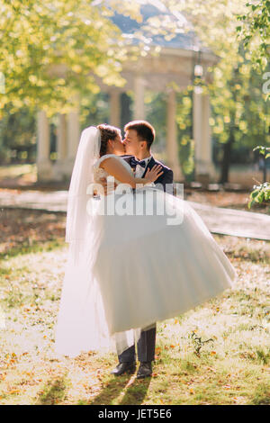 Le marié est maintenant la mariée et s'embrasser dans le parc ensoleillé. Banque D'Images