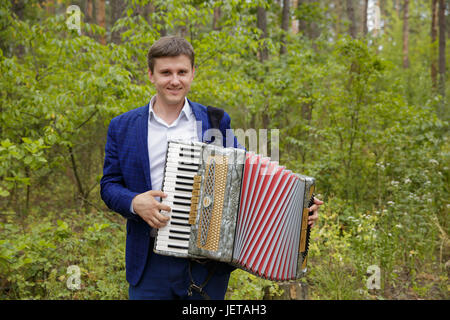 L'homme joue sur un accordéon électronique dans la lumière naturelle Banque D'Images