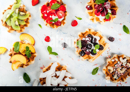 Ensemble de plaquettes soft belges avec différents toppings - pêche, mûres, framboises, fraises, noix de coco, noix de cajou, les fraises, la menthe. La lumière Banque D'Images