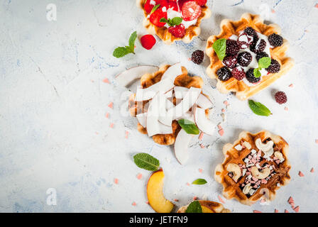 Ensemble de plaquettes soft belges avec différents toppings - pêche, mûres, framboises, fraises, noix de coco, noix de cajou, les fraises, la menthe. La lumière Banque D'Images