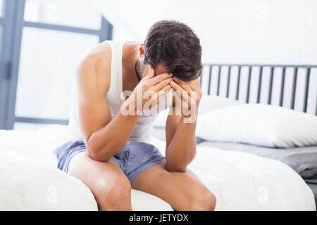 Tendu young man sitting on bed Banque D'Images