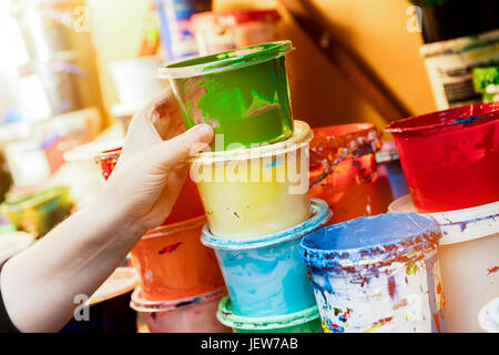 Pour atteindre l'artiste un liquide contenant de peinture. Travaillant dans un atelier Banque D'Images