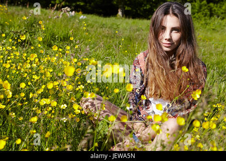 Young woman sitting on meadow Banque D'Images