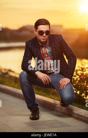 Portrait de jeune homme dans la mode des lunettes de soleil au coucher du soleil Banque D'Images