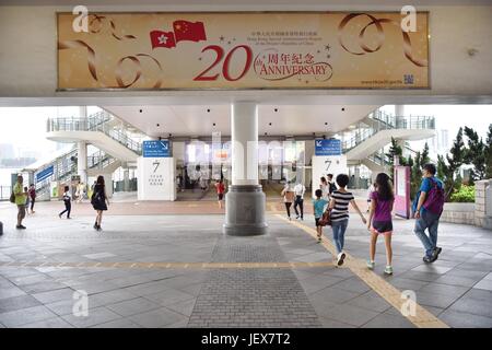 Hong Kong, Chine. 27 Juin, 2017. Les gens marchent sous un panneau marquant le 20e anniversaire de la déclaration de Hong Kong à la patrie à Hong Kong, Chine du sud, le 27 juin 2017. Credit : Wang Xi/Xinhua/Alamy Live News Banque D'Images