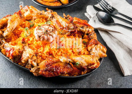 La cuisine de l'Afrique de l'Ouest. Riz Jollof avec des ailes de poulet et poêlée de bananes plantains.sur table en pierre grise. Copy space Banque D'Images