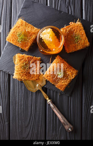 De délicieuses pâtisseries du Moyen-Orient avec les pistaches et miel frais sur une plaque. vertical Vue de dessus Banque D'Images