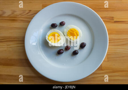 Un apéritif d'un œuf dur et des olives sur un plat blanc Banque D'Images