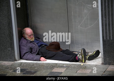 Sans-abri mendicité chômeur ancien senior citizen dao couché dans une porte avec hat inappropriée Banque D'Images