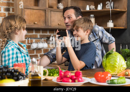 Famille heureuse dans la cuisine, père et fils de prendre Photo De fille à la cuisson des aliments sur Cell Smart Phone La préparation de repas sains Banque D'Images