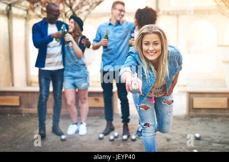 Jolie jeune femme jetant une Boule de petanque tout en noir et blanc de la communication de l'équipe et de boire une bière. Banque D'Images