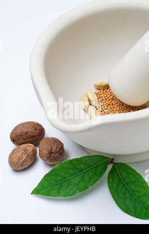Close up d'un mortier et pilon en grès contenant un mélange d'épices entières, avec muscade et les feuilles de laurier à la surface à l'extérieur. La verticale (elevated view Banque D'Images