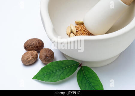 Close up d'un mortier et pilon en grès contenant un mélange d'épices entières, avec muscade et les feuilles de laurier à la surface à l'extérieur. (Fil horizontal Banque D'Images