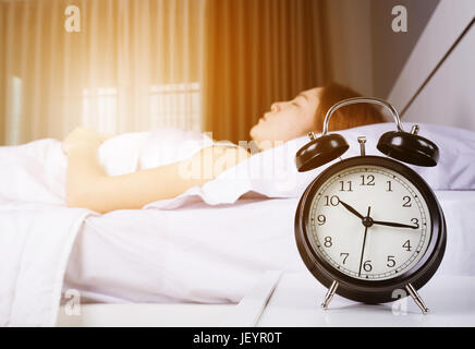 Afficher l'horloge 10h00. Et la femme dort sur le lit avec la lumière du soleil du matin Banque D'Images