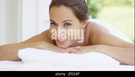 Femme sourit et se détend sur table de massage Banque D'Images