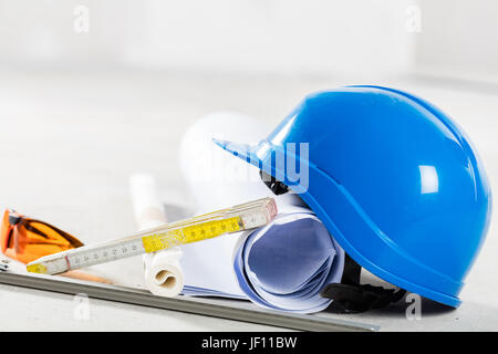 Casque, lunettes de sécurité et les bleus sur le site de construction. Bâtiment et outils engineereing close up. Banque D'Images