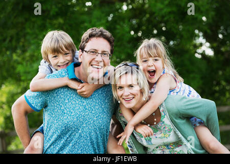 Les parents, un homme et une femme debout dans un jardin, donnant à leurs fils et fille se greffe. Banque D'Images
