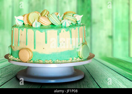 Gâteau crémeux vert avec des macarons sur fond de bois vert Banque D'Images