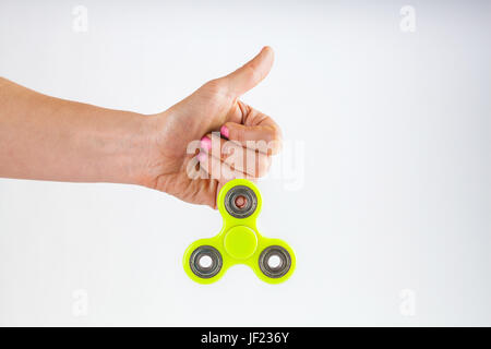 Avec main de femme jaune rose ongles tenant fidget spinner avec thumb up isolated on white background with copy space Banque D'Images