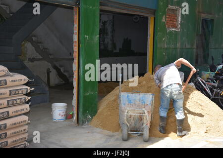 Homme creuser dans le sable pour mélanger avec du ciment pour réparer un bâtiment ancien à Taiwan. Cela signifie que les nouveaux locataires à l'avoir fait avant d'ouvrir. Banque D'Images