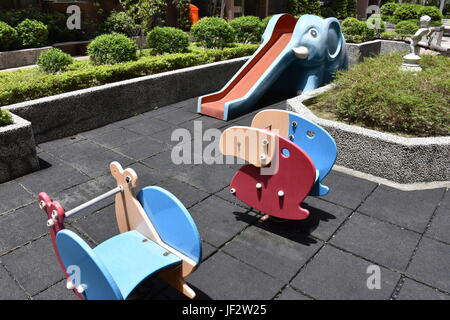 Aire communautaire avec glissoire éléphant bleu et en faisant tourner les jouets au jardin pour les enfants à jouer et apprécier. Banque D'Images