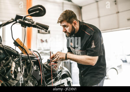 Mécanicien moto réparation vélo noir sport électronique. Beau travail de mécanicien en atelier de réparation automobile. Banque D'Images