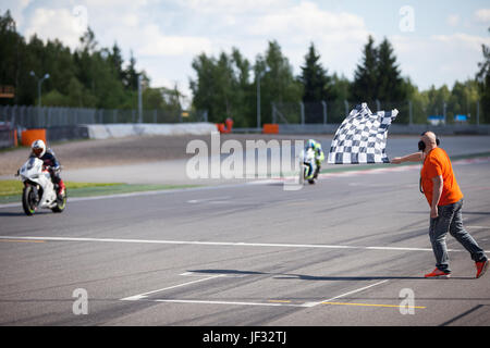Man holding et agitant le drapeau à damiers à l'arrivée de la course Banque D'Images