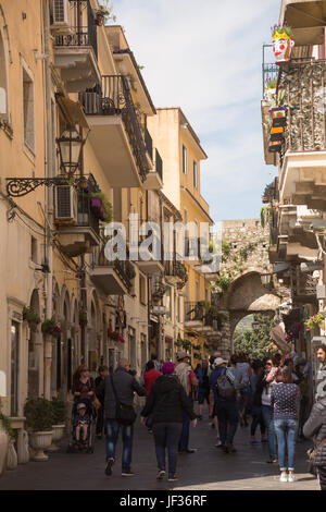 Les personnes qui s'y passé commerces et bâtiments près de arch dans rue commerçante piétonne Corso Umberto, Taormina, province de Messine, Sicile, Italie. Banque D'Images