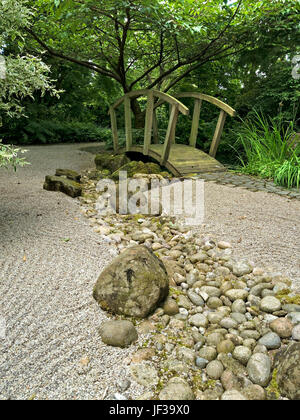 Jardin de style Zen japonais avec du gravier ratissé, pont et rivière en bois orné de galets, le Barnsdale Jardins, Rutland, England, UK. Banque D'Images