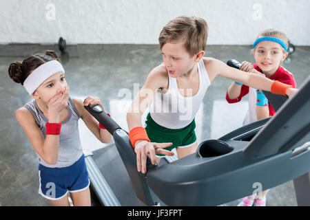 Groupe des petits enfants dans les vêtements de sport l'exercice sur tapis roulant dans une salle de sport, les enfants de l'école sport concept Banque D'Images