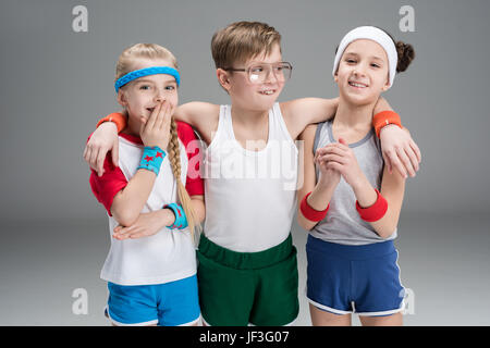 Portrait of smiling enfants actifs dans sportswear isolé sur gray Banque D'Images