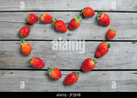 Vue de dessus de fraises fraîches en forme de coeur sur table en bois, petits fruits sur bois concept Banque D'Images