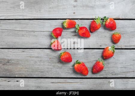 Vue de dessus de fraises fraîches en forme de coeur sur table en bois, petits fruits sur bois concept Banque D'Images