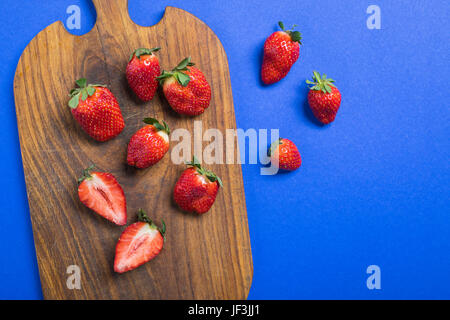 Vue de dessus les fraises rouges frais sur planche à découper en bois isolé sur baies bleu, top view concept Banque D'Images