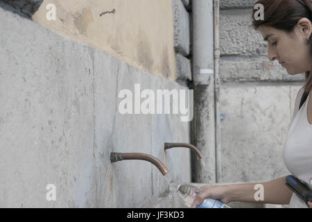 Une femme de remplir une bouteille avec l'eau potable dans la région de fontaine publique, Rome, Italie Banque D'Images