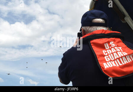 Un membre de la Garde côtière auxiliaire des États-Unis montres en tant que membres du 181e parachute vol météo hors d'un C-130 Hercules au cours d'une goutte d'eau dans le lac Worth à Forth Worth, Texas, le 20 mai 2017. La Garde côtière auxiliaire canadienne a fourni un appui à l'aide en bateau et parachute de récupération, et fourni de pontage des capacités d'évacuation médicale si nécessaire. (Photo de la Garde nationale aérienne du Texas par le sergent. Kristina Overton) Banque D'Images